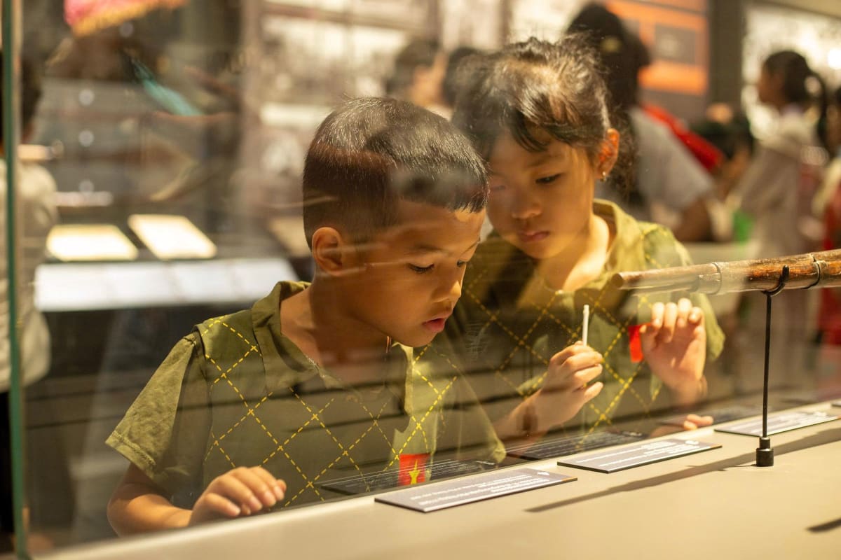 Anak-anak berdiri mengamati sebuah pameran di dalam museum
