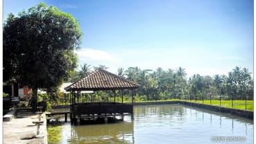 Kolam di kawasan Cibulan, Kuningan, dengan gazebo kayu di atas air dan pepohonan kelapa; foto dari 2010.