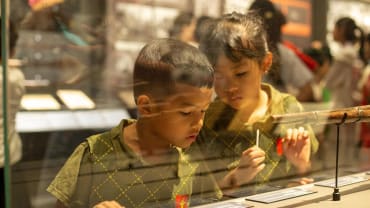 Anak-anak berdiri mengamati sebuah pameran di dalam museum