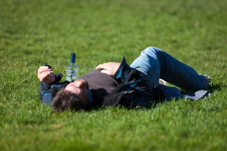 Seorang dewasa berbaring di rumput dengan botol air di sampingnya, beristirahat dan pulih setelah mabuk perjalanan