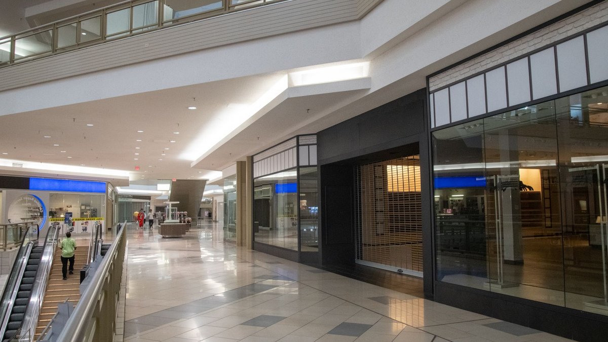 Spacious and contemporary mall interior with closed stores and escalator.