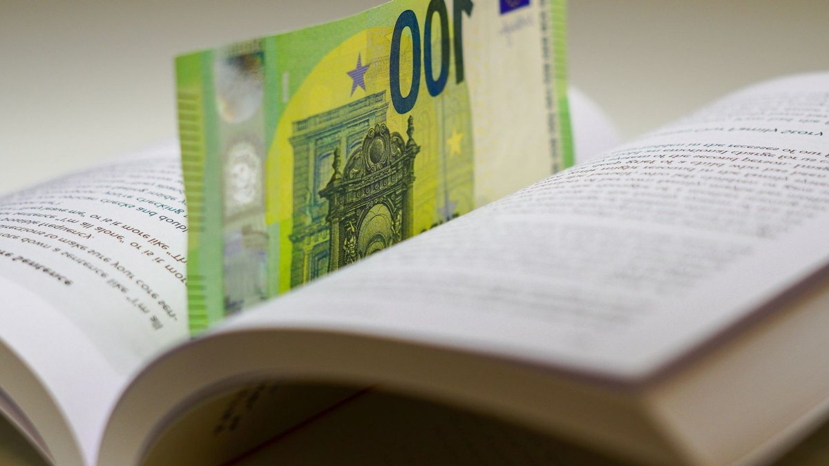 A 100 euro bill used as a bookmark between open pages of a book, symbolizing wealth and knowledge.