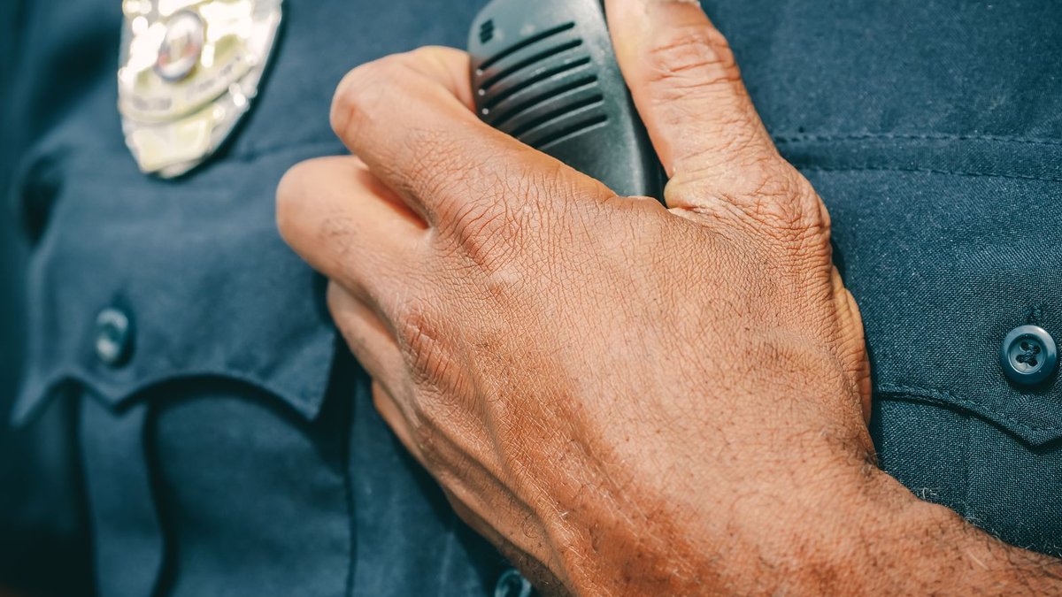 A police officer in uniform holding a radio communicator, showcasing professional authority.