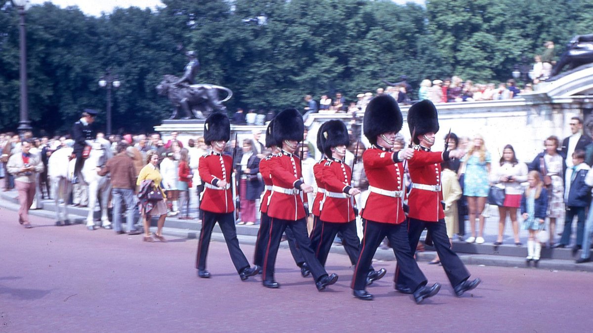 Meghan Markle's UK Strategy Targets Princess Kate's Spotlight Marching royal guards in traditional uniforms near a bustling crowd.