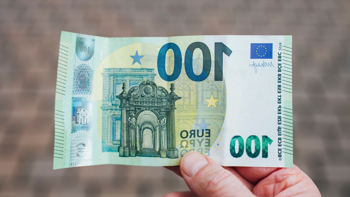 ECB Launches Digital Euro Beta Pilot for Online Merchants Close-up photo showing a person holding a 100 euro banknote against a blurred background.
