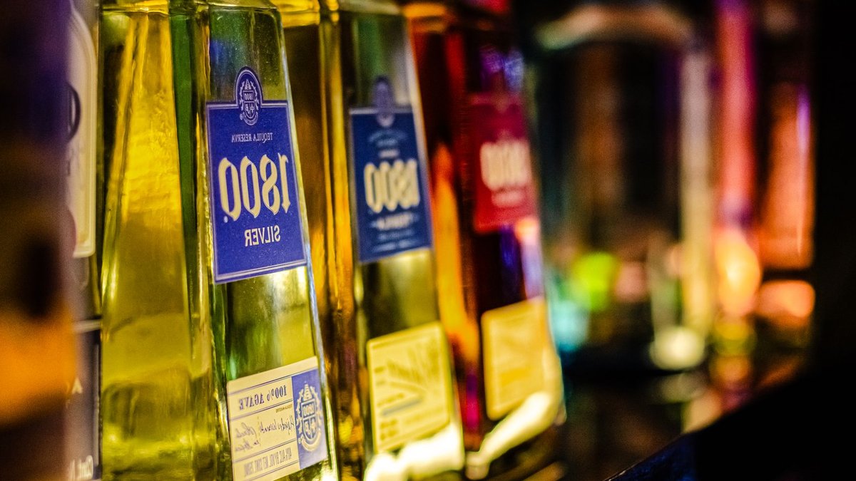 Colorful liquor bottles lined up on a bar shelf, highlighting tequila selection.