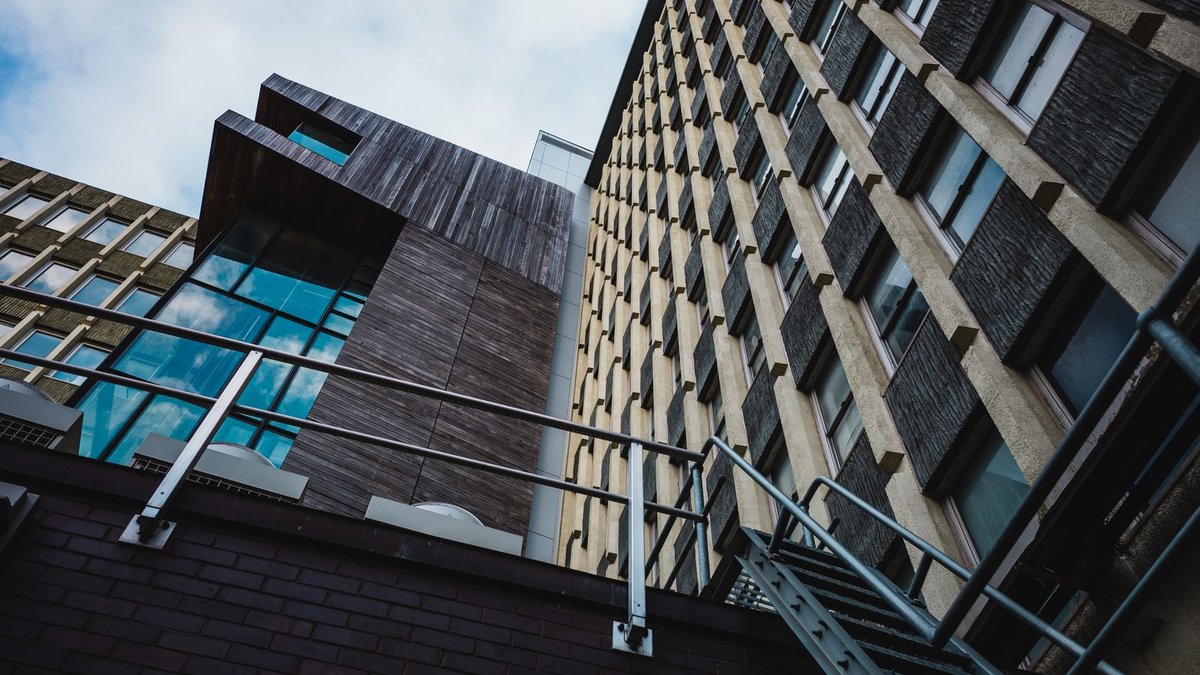 Low angle view of modern city buildings with a striking architectural design under a clear sky.