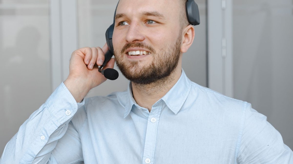 Smiling call center agent wearing a headset providing customer service in an office environment.