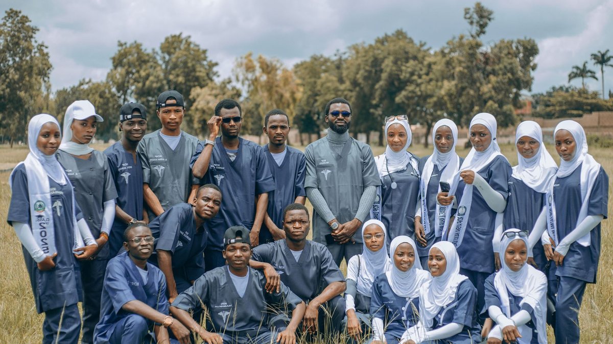 A group of diverse medical students in uniforms posing outside in a field, showcasing unity and education.