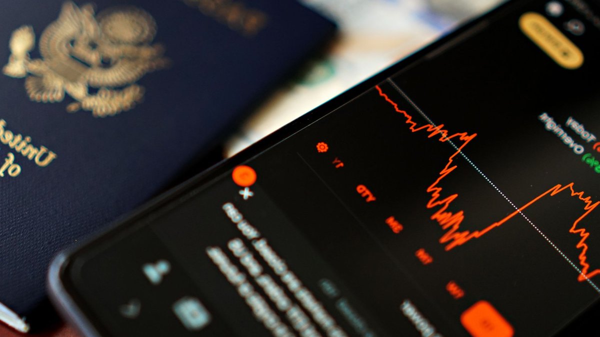 Ledger reassures users after third-party data breach Close-up of a smartphone displaying stock data next to a US passport, suggesting travel and finance themes.
