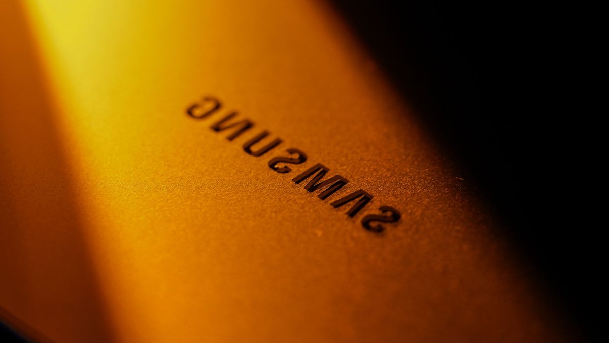 Samsung’s tech breakthroughs that redefined smartphones Dramatic close-up of a Samsung electronic device highlighted by golden lighting and shadows.