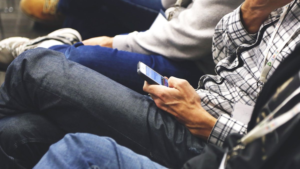 MOBILITY ADO Launches New Division for Talent Mobility Solutions People sitting at a conference casually checking smartphones, communicating and networking.