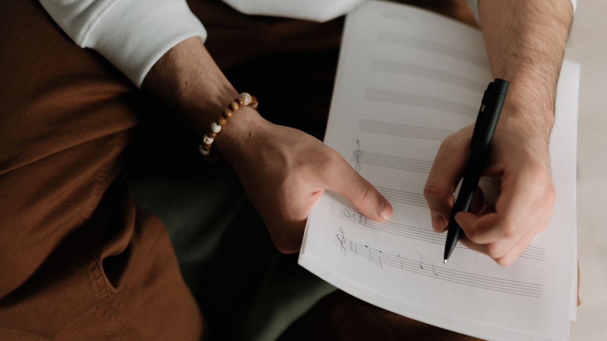 Founder steps back to let business thrive A songwriter composing lyrics and musical notes on sheet music.