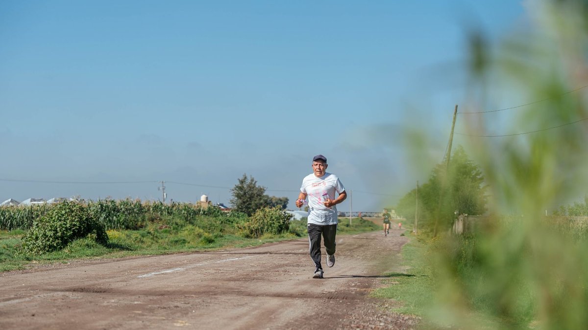 Adult man jogging on a rural dirt road, showcasing outdoor fitness and health in a peaceful countryside.