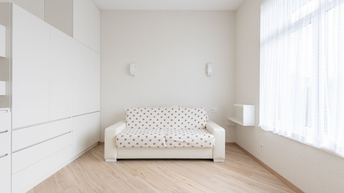 Couple Weighs Paying S$280K More for a Larger HDB Flat Interior of modern living room with sofa placed on parquet between window and white cupboards in light apartment with minimal