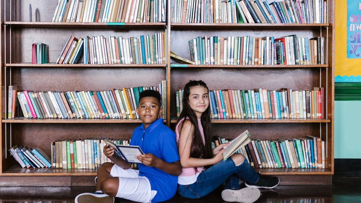 US Reading Proficiency Drops Sharply in Nationwide Study Person reading a book while surrounded by people looking at their phones in a crowd of blue-toned figures.