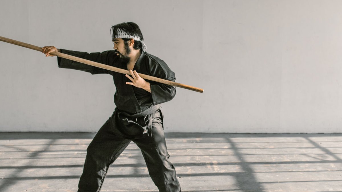 Unanswered calls drive patients to competitors-AI offers a solution Martial artist in black gi practicing with bo staff in spacious room.