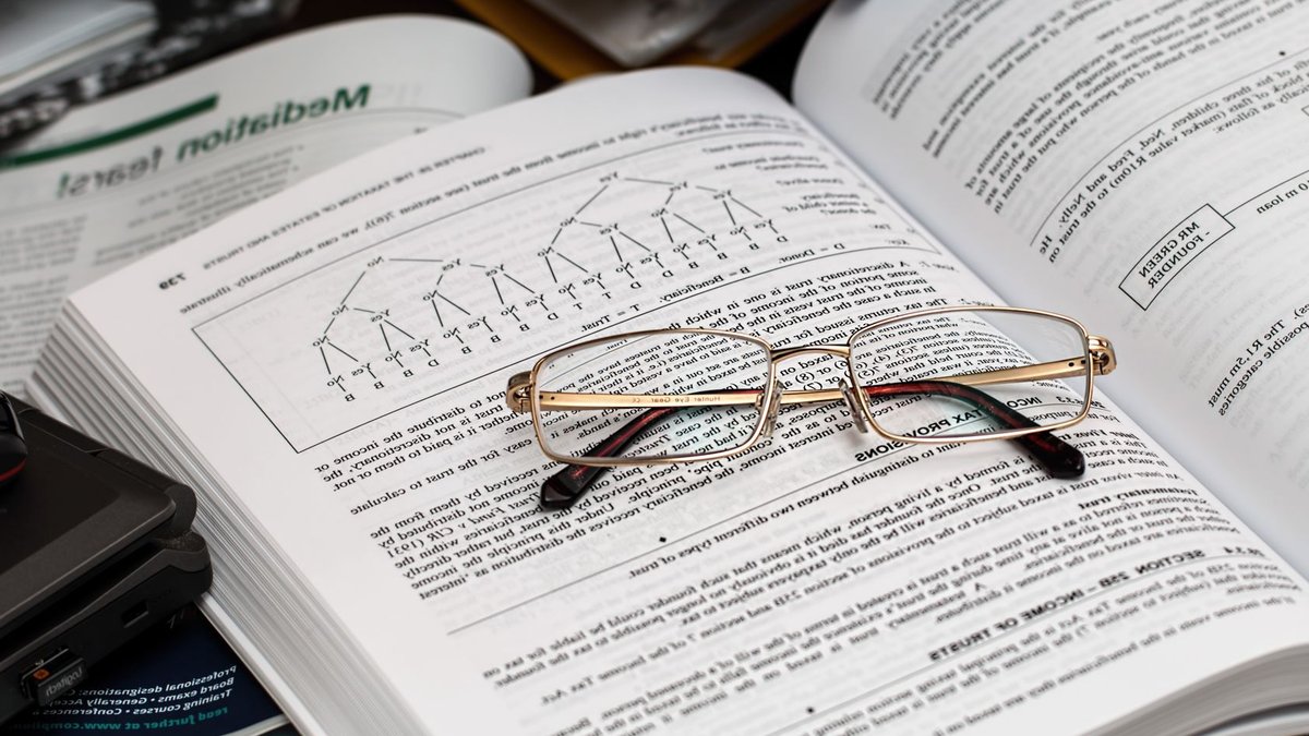 Non-linear careers rise as Gen Z blends work, study An open book with reading glasses, surrounded by study materials and a laptop, ideal for education themes.