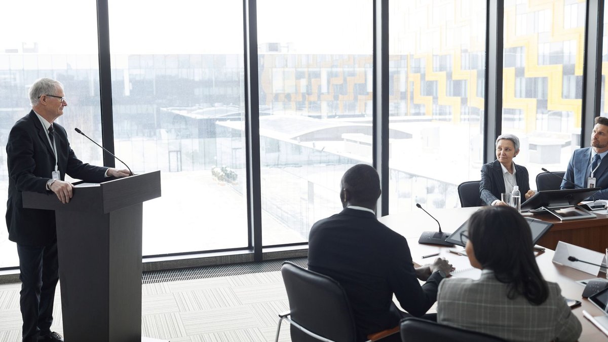 Corporate professionals engaged in a formal business meeting in a modern conference room setting.