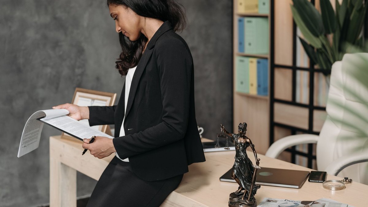Clio Partners with WOW to Boost Spanish Law Firms' Tech A professional woman in a business suit reviews legal documents at her office desk.