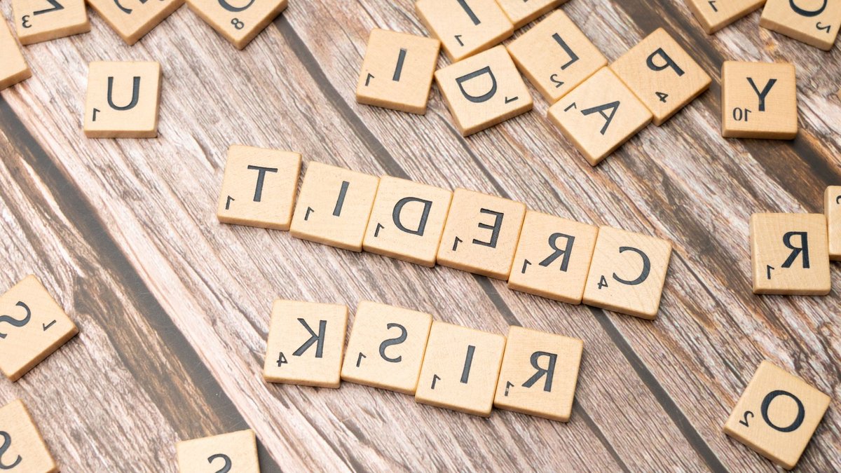 Central banks pose threat to fintech stability Scattered wooden letter tiles spelling 'credit risk' on a rustic wooden surface.