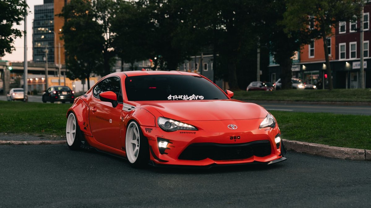 Celebrities Showcase Custom Cars at Indonesia Auto Expo Stylish red sports car with custom modifications parked in an urban environment during daylight.