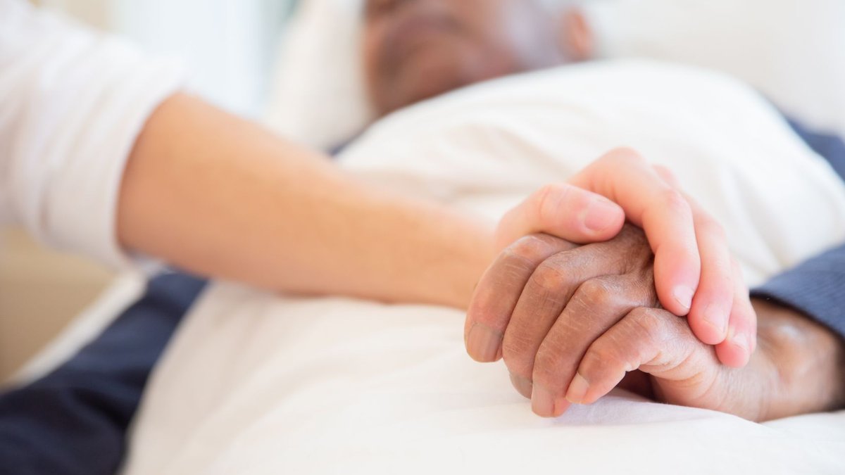 Ascension to sell Mercy Care stake to Aetna A comforting gesture as a hand holds another in a hospital setting, symbolizing care and support.