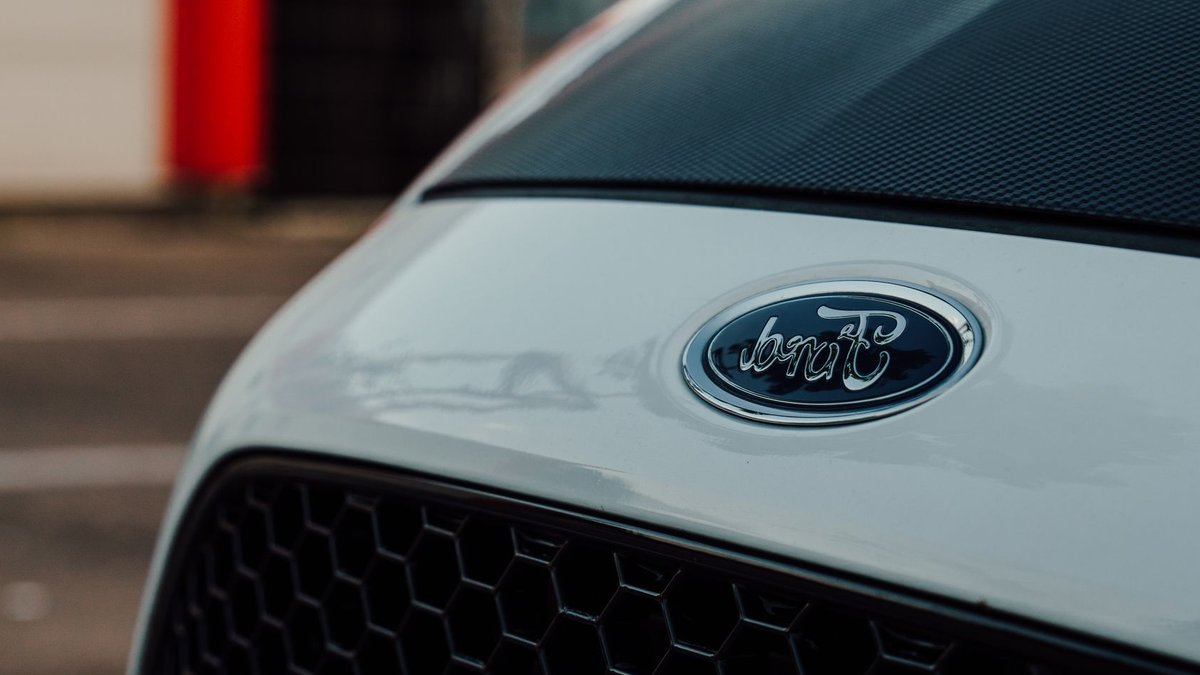 Ford opens invite list for Fathom electric pickup Detailed close-up image showcasing a white Ford car emblem on the vehicle's grille.