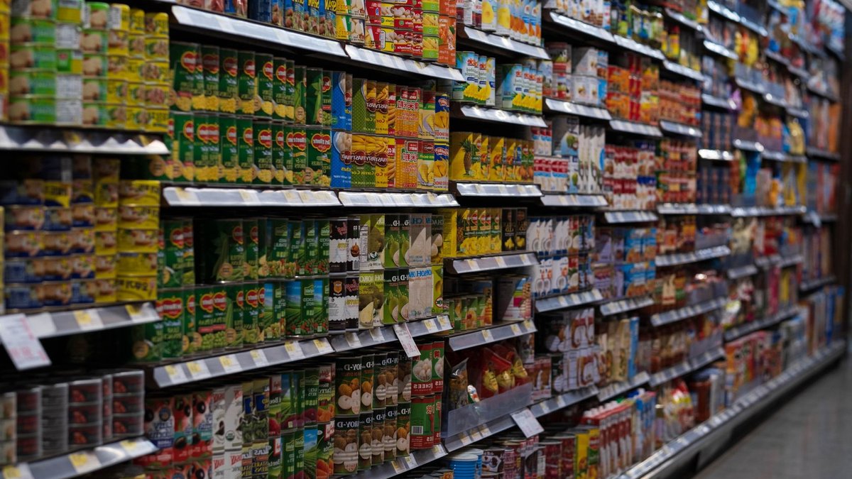 Tesco expands Clubcard to 500 new partner brands A supermarket aisle filled with various canned goods on shelves, showcasing retail diversity.