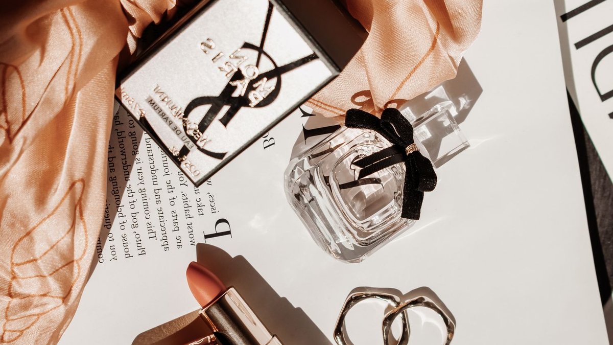 Sephora's London beauty festival debuts, M&S partnership announced Sophisticated flat lay featuring luxury beauty products, including perfume and lipstick, with a stylish scarf.