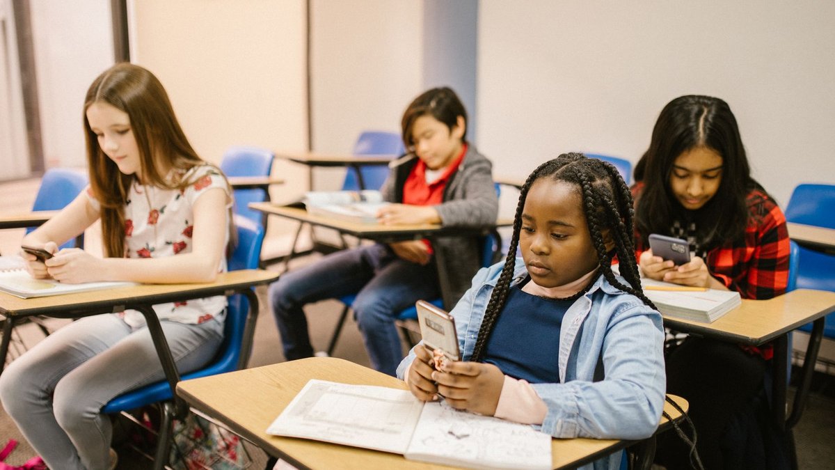 AI chatbots boost student learning in Ghana and Sierra Leone A group of four students in a classroom using smartphones and notebooks during a lesson.