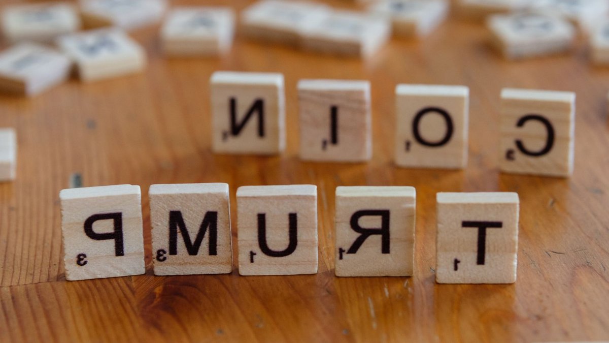 Scrabble tiles spelling 'TRUMP' on a wooden table, creating a political theme.
