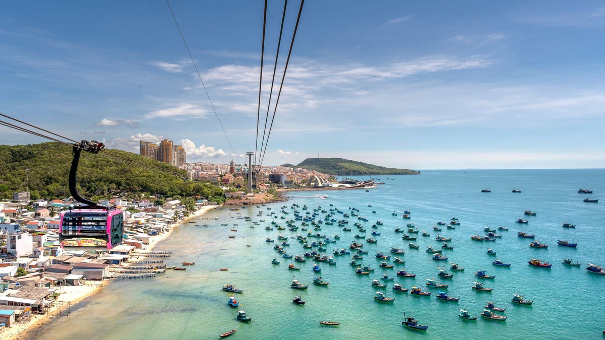 Malaysia leads US-backed Southeast Asia data cable project A breathtaking aerial view of a cable car soaring over a vibrant seascape in Vietnam, surrounded by colorful boats and lush l