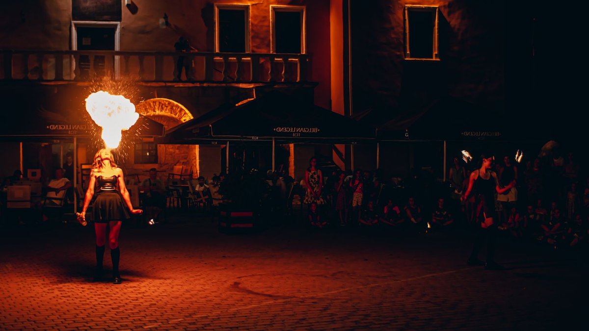 A captivating night street performance with a fire-breathing entertainer in front of an audience.