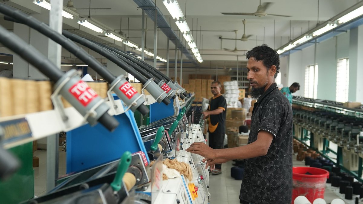 Pirelli and BKT team up for India’s premium tyre production Worker operating textile machinery in a factory, focusing on production efficiency.