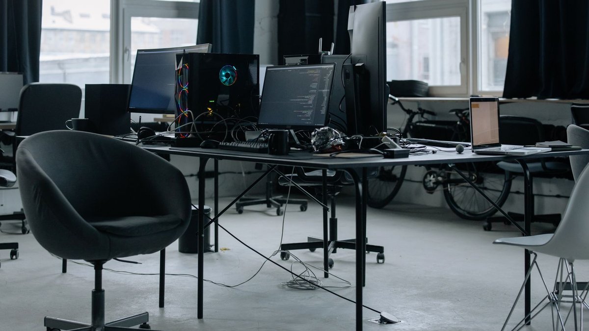 Discover a modern office workspace with computers, chairs, and natural light from large windows.