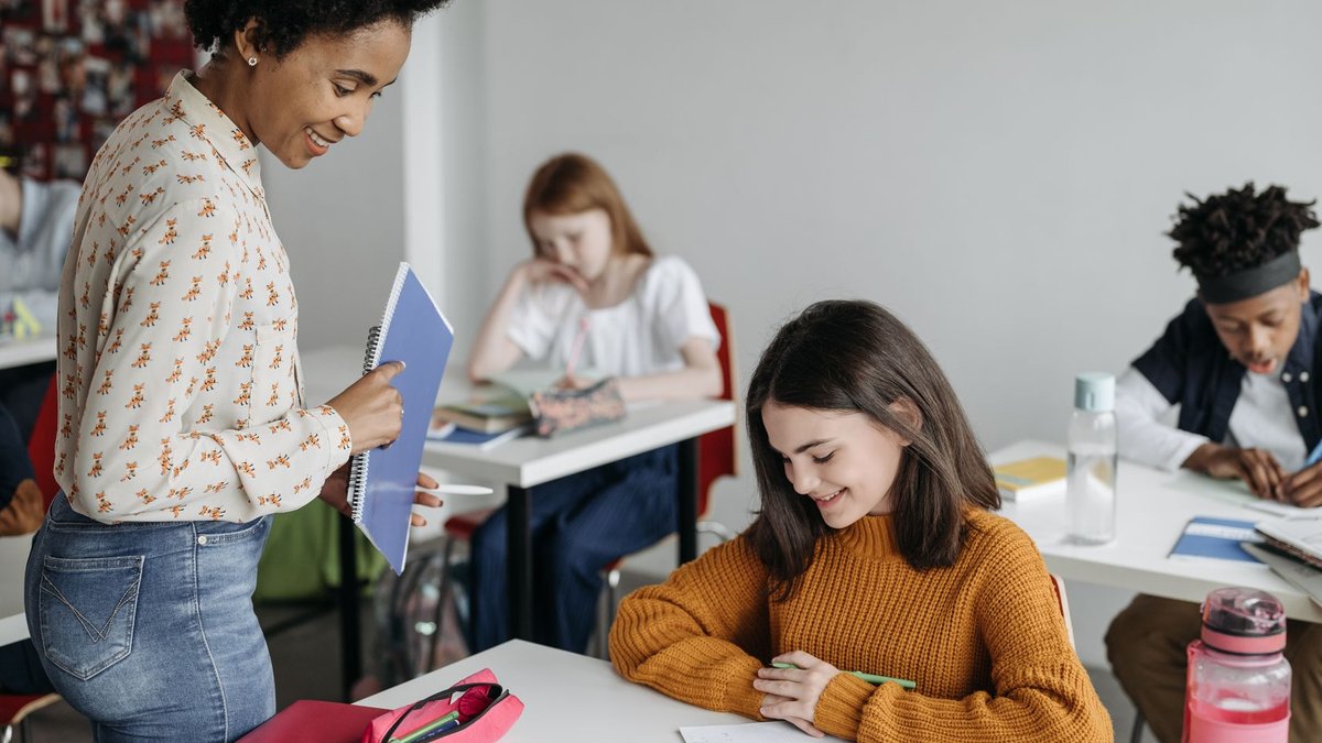 Teacher assisting students in a classroom setting, fostering a learning environment.