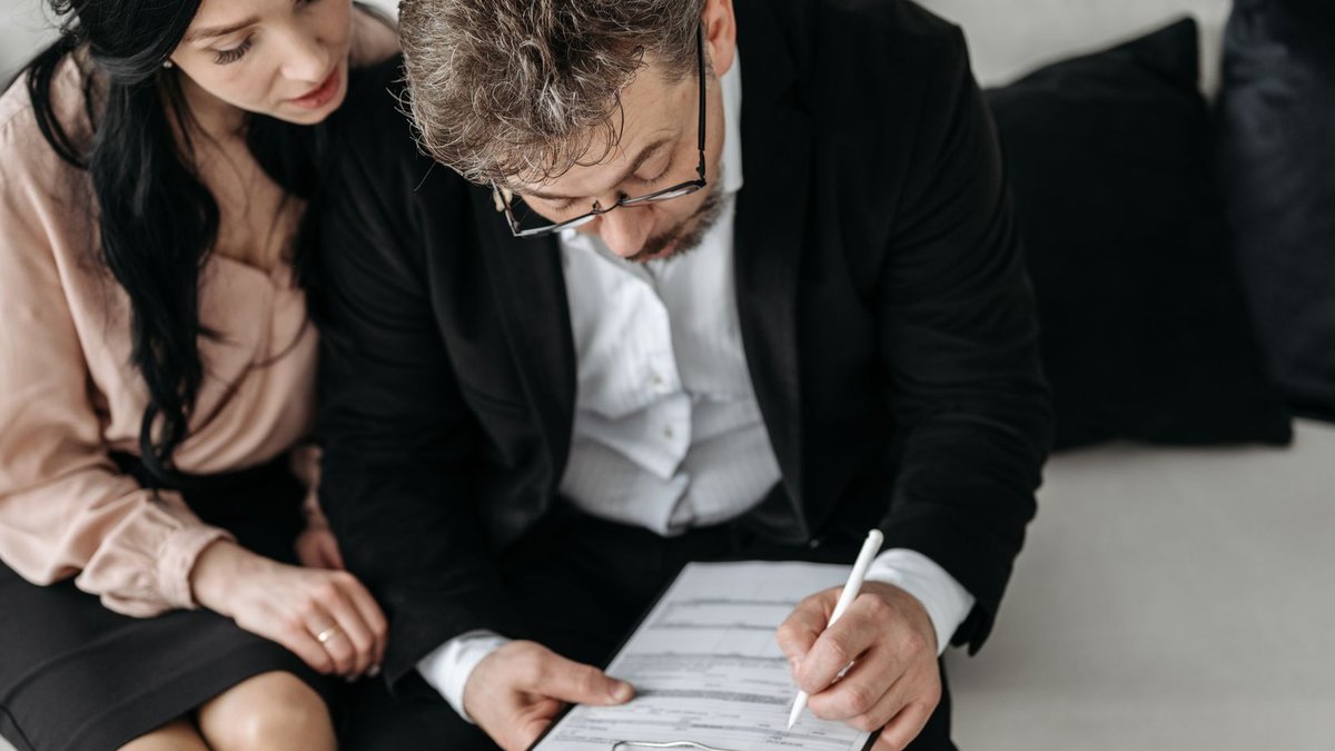 Couples’ Pension Planning Offers Financial Edge, Experts Say An adult couple sitting together reviewing documents in a modern indoor setting.