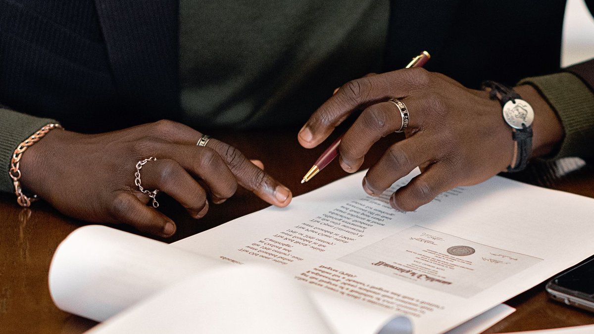 Ecobank ties Africa to China’s trade finance network A business professional's hands signing a document at a desk, focusing on details.