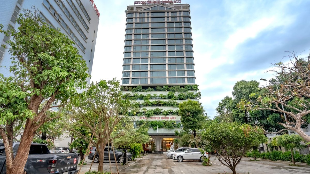 A modern luxury hotel with greenery in a bustling city environment.