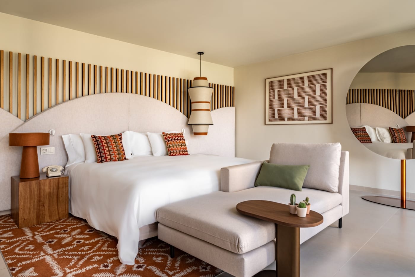 Una suite del Kimpton Atlântico Algarve con cabecero ondulado y alfombra terracota