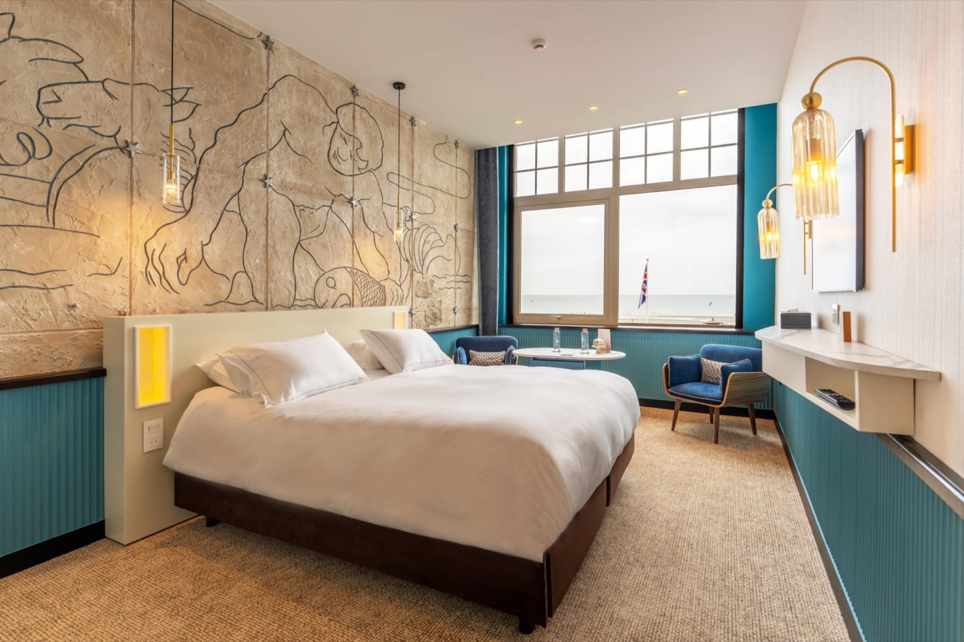 La júnior suite de L'Atlantic en Wimereux, con frescos de líneas sencillas y paneles de madera azul