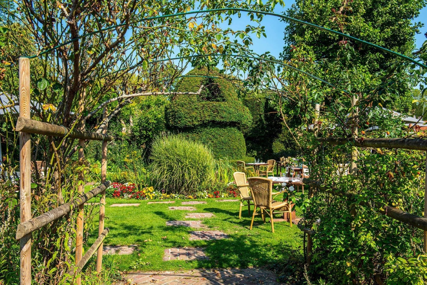 El jardín inglés de Le Château de Montreuil bajo una pérgola de rosales