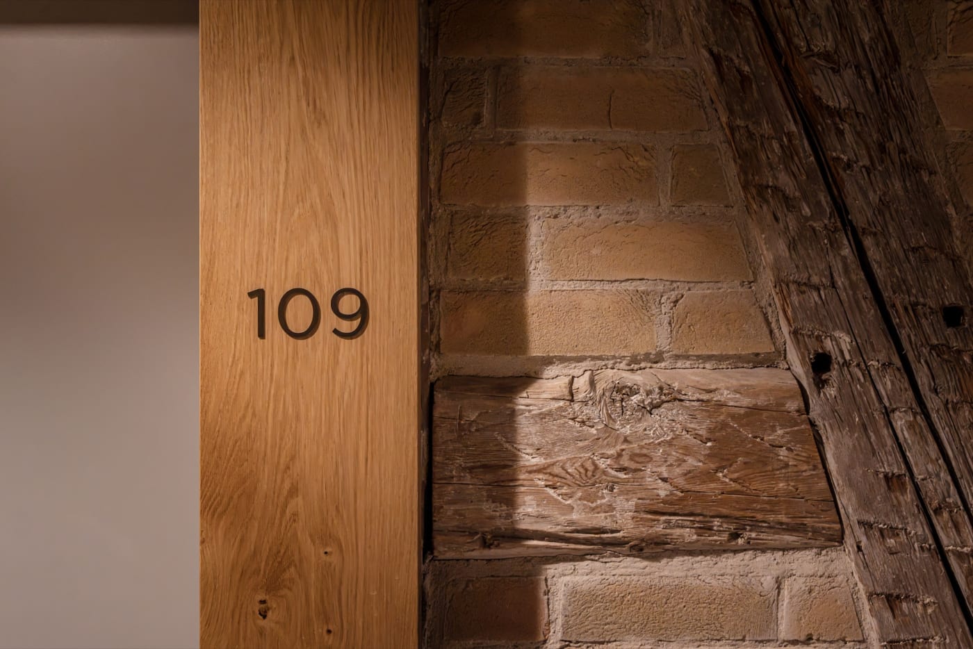 An oak bedroom door on an original brick wall at Les Haras