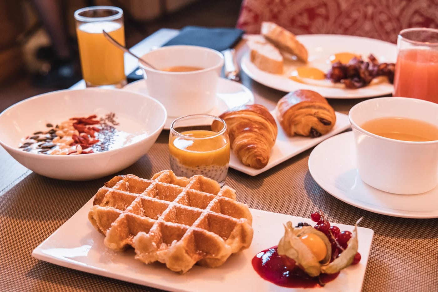Ein am Tisch serviertes Frühstück mit Waffel und Croissant im Cour du Corbeau