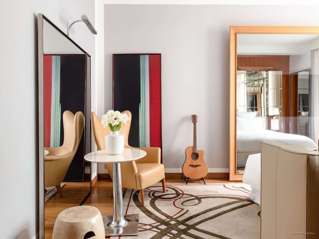A room with a guitar and contemporary artwork hanging on the wall