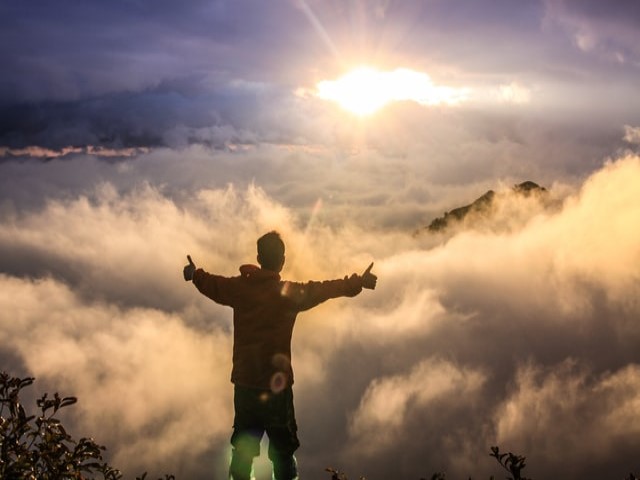 Man on mountain top feeling successful