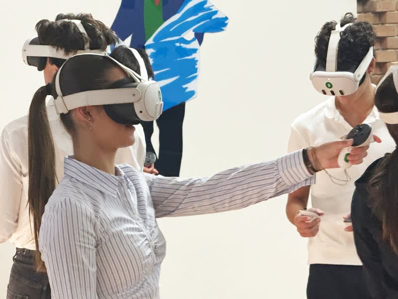 Several young people wearing white virtual reality headsets and holding motion controllers during an immersive training session