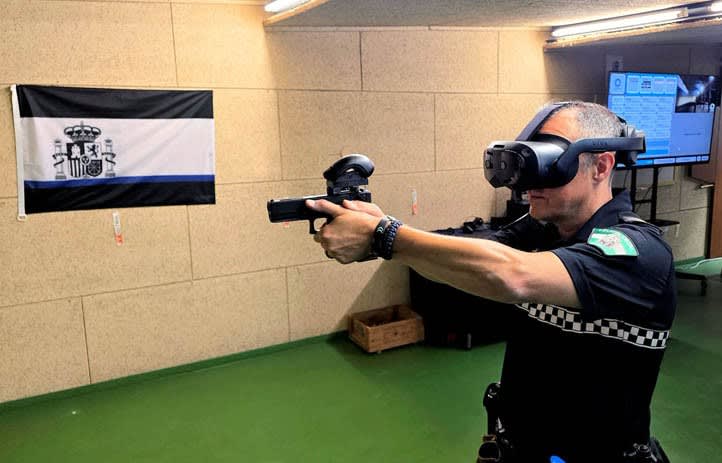 A Marbella Local Police officer training in the Octopus simulator at the force's shooting range, aiming a replica service pistol fitted with a motion tracker.