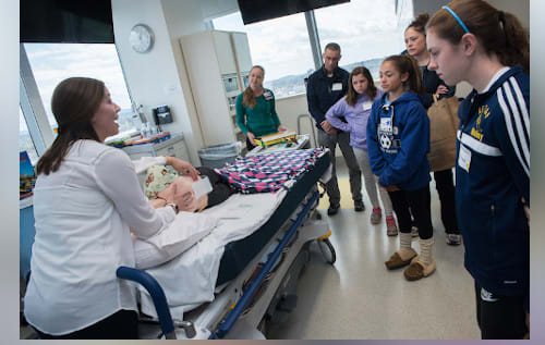A clinician walks a group of patients and family members through an operating room at Boston Children's Hospital.
